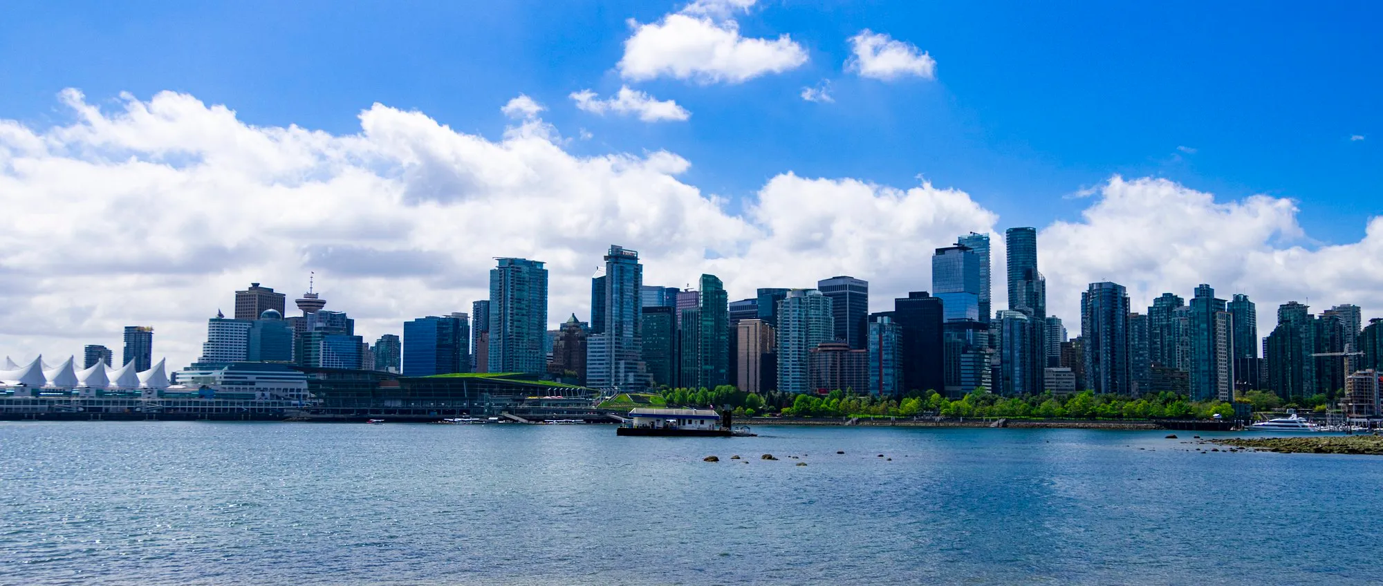 The downtown skyline across Coal Harbour from Brockton Point under fair-weather cloud