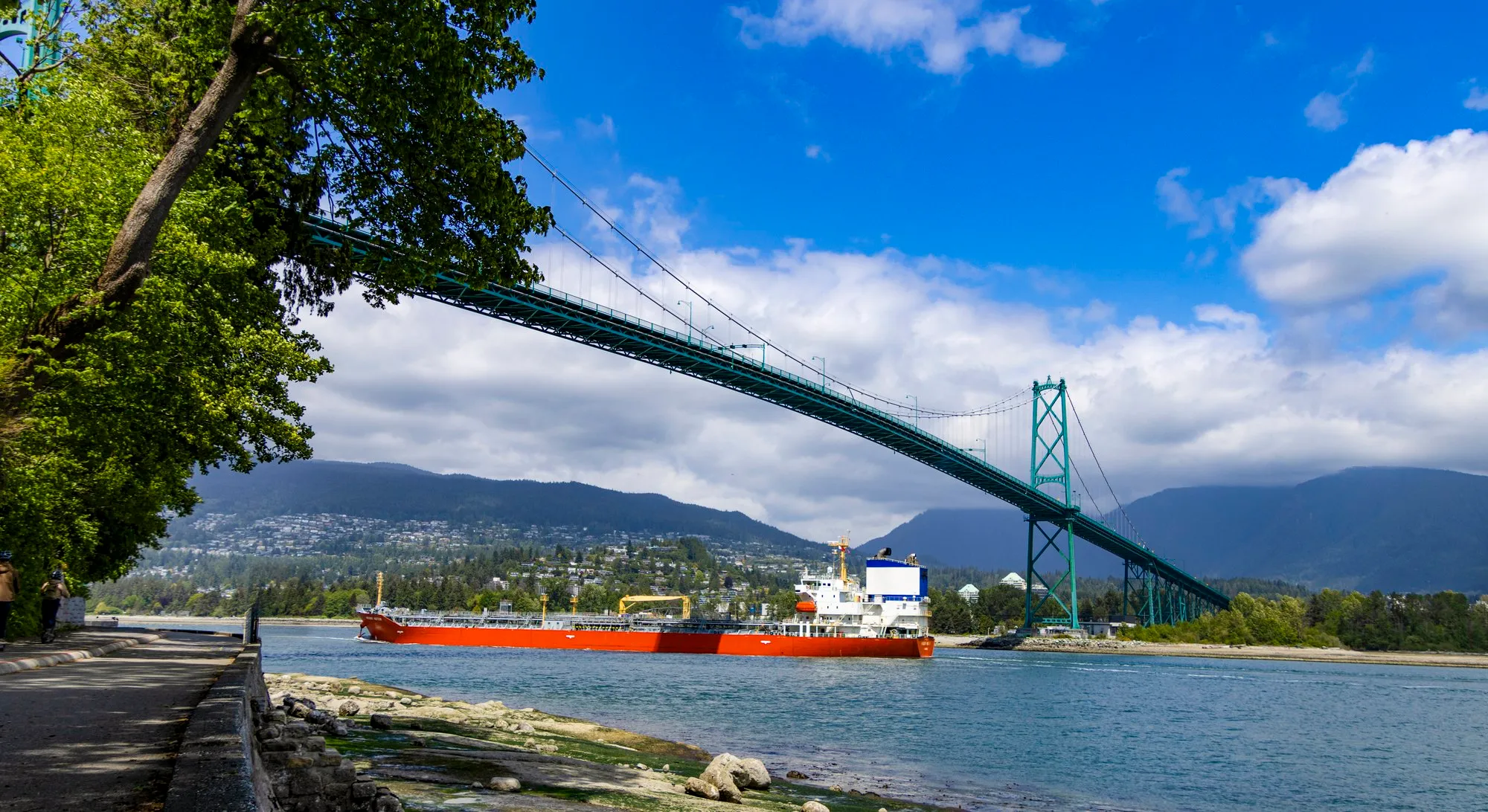 A red freighter passing under Lions Gate Bridge