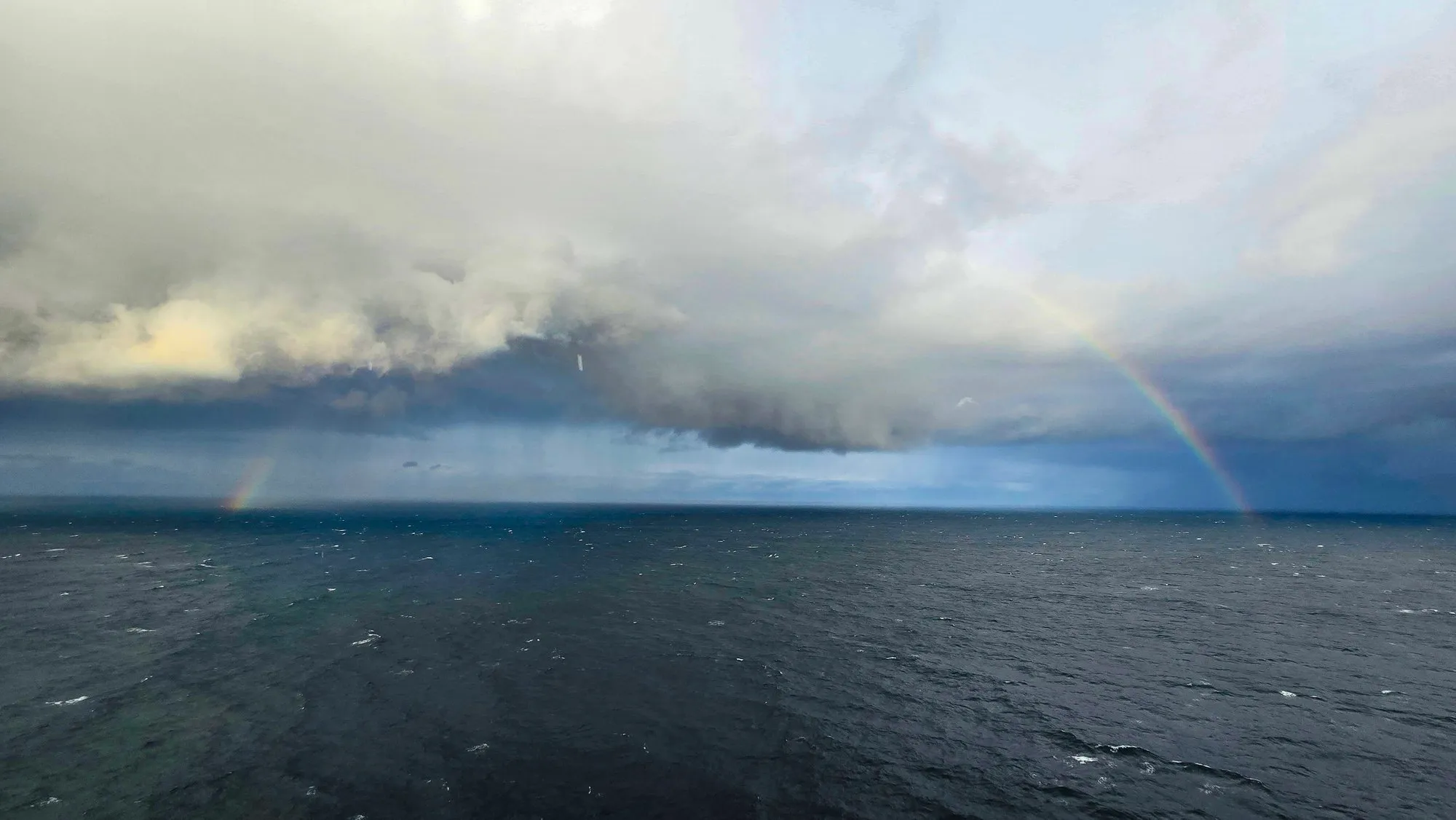 A rain squall and a faint rainbow over the open sea south of Sitka