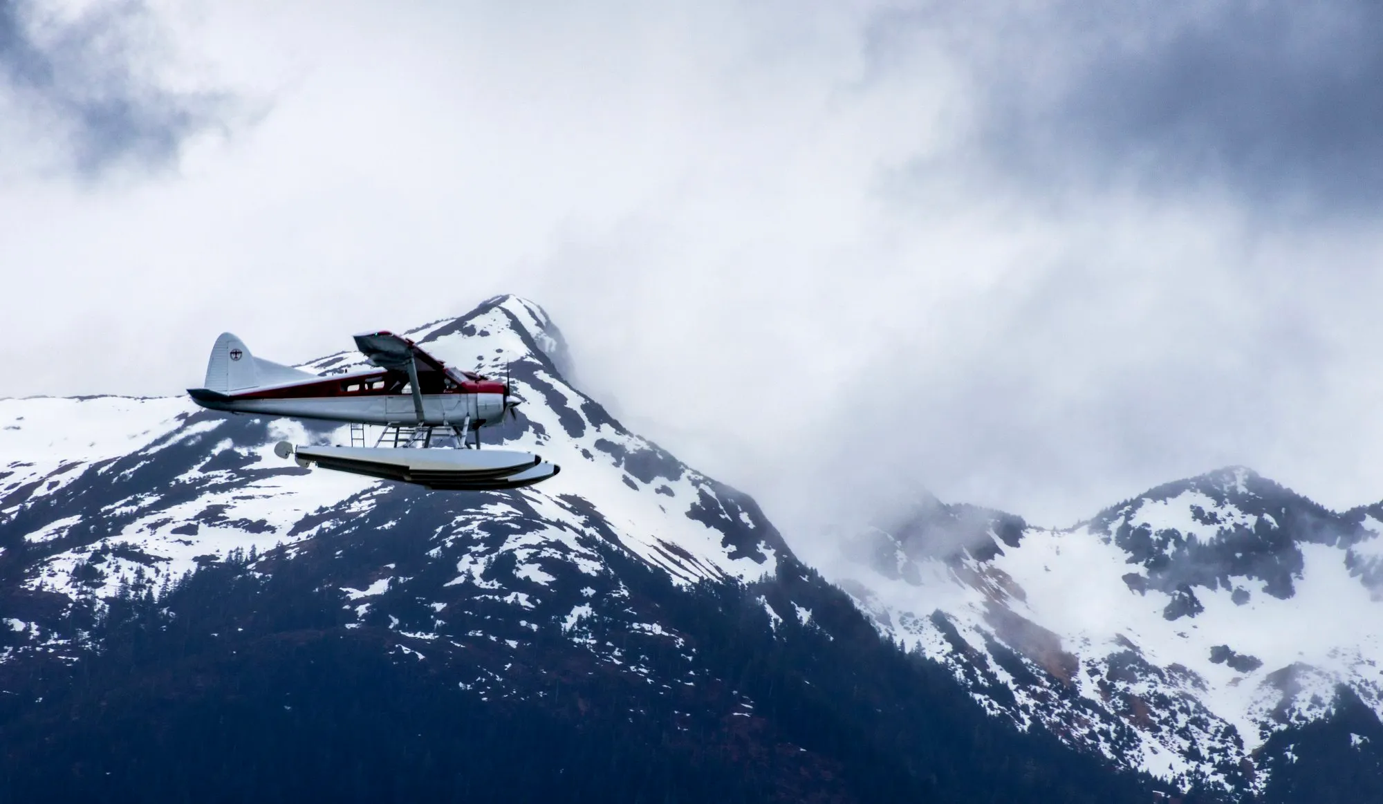 A floatplane crossing in front of snow covered mountains near Sitka, with the lens at 246 mm