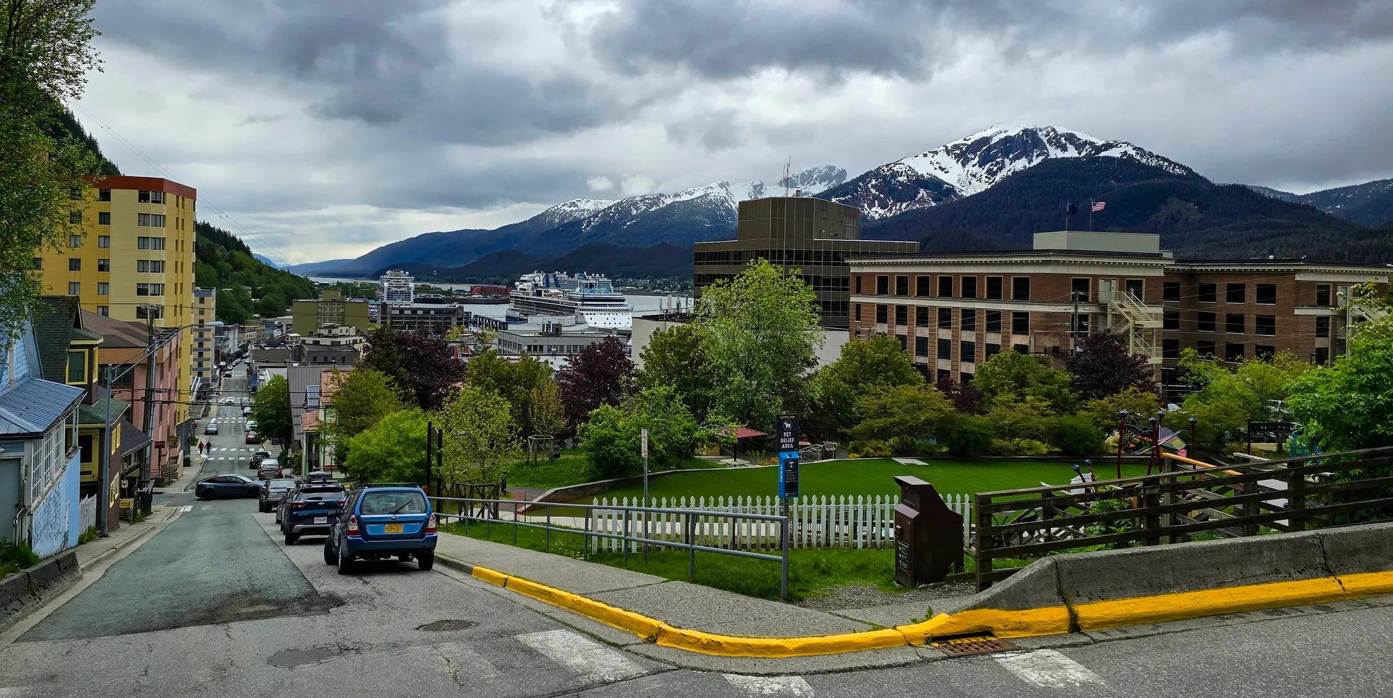 A steep street in Juneau looking down toward the channel, snow on the peaks across it