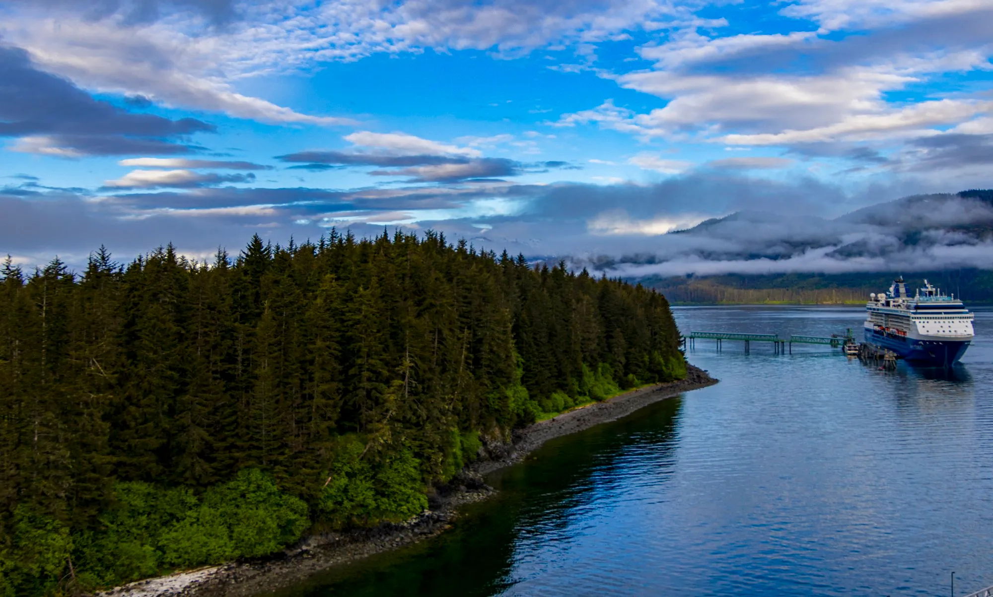Icy Strait Point at dawn from the ship, the pier and the forest in still water