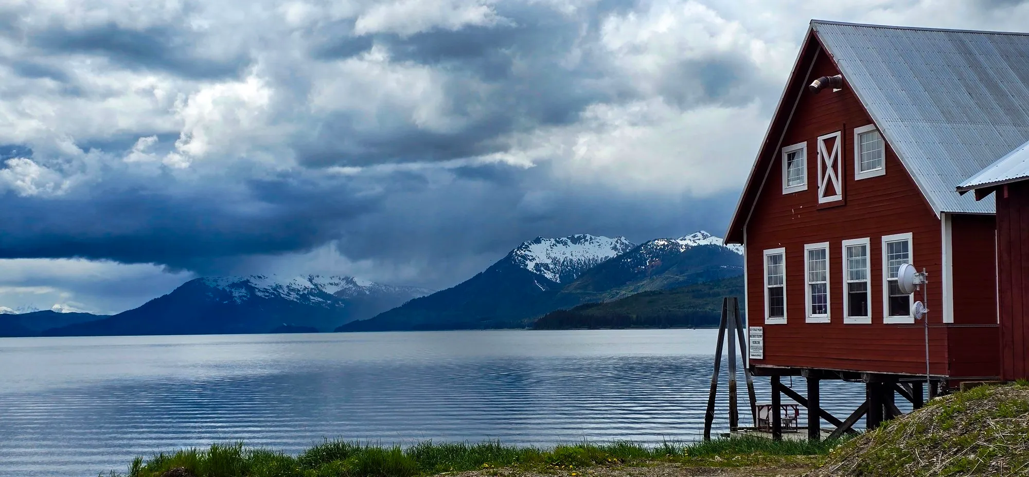 The red cannery building at Icy Strait Point with the bay and mountains behind it