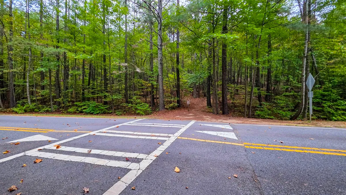 A painted crosswalk across a two-lane road, the trail going on into the woods on the far side