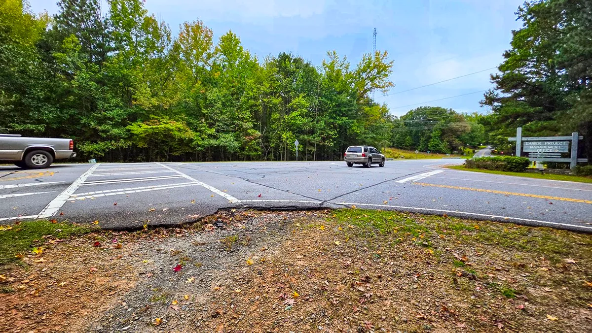 Where the trail meets a two-lane road beside a parking area and the Lanier Project Management Office sign