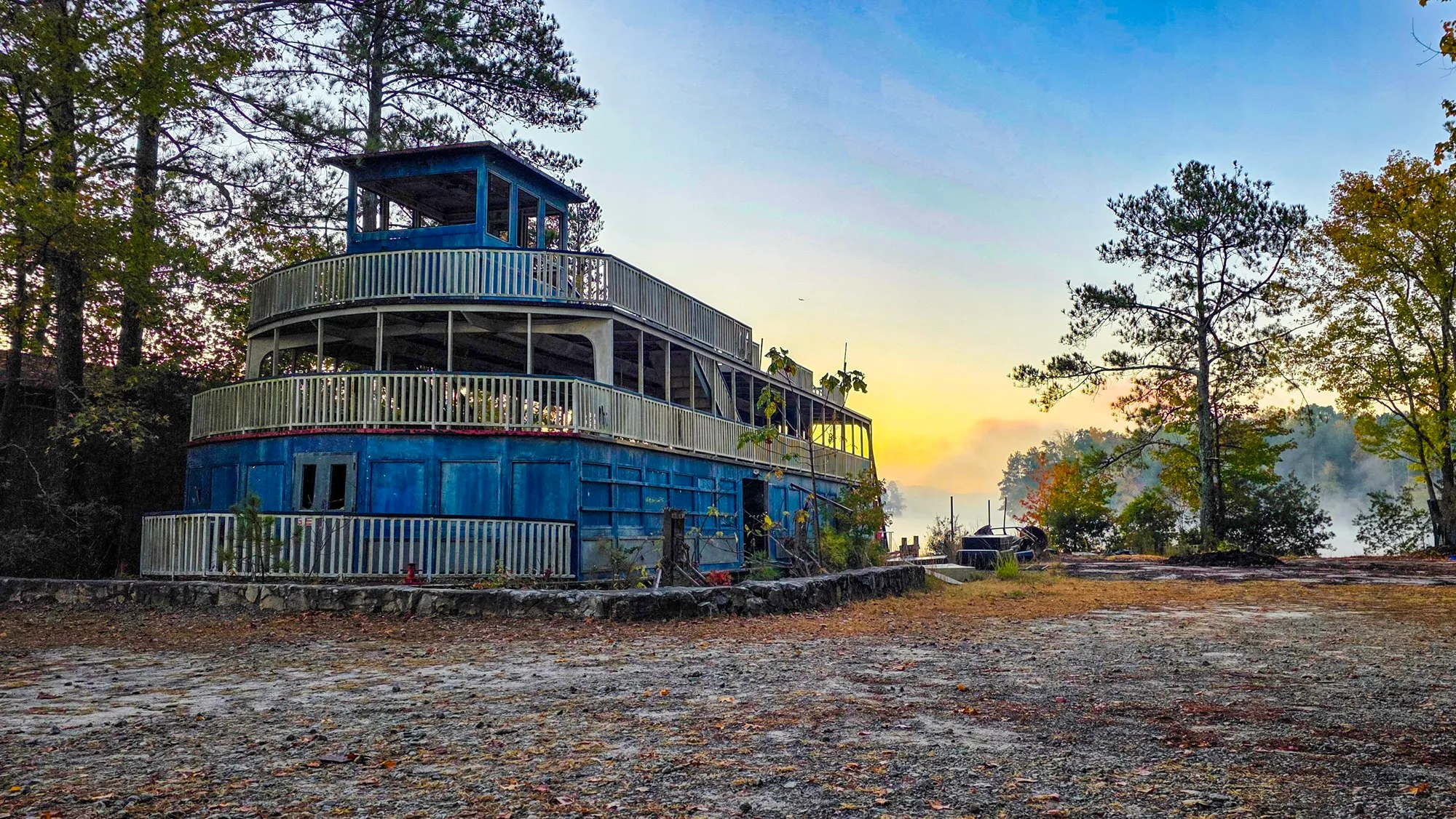 The riverboat on its pad with mist on the lake behind it, the pilothouse against a pale sky, leaves on the ground