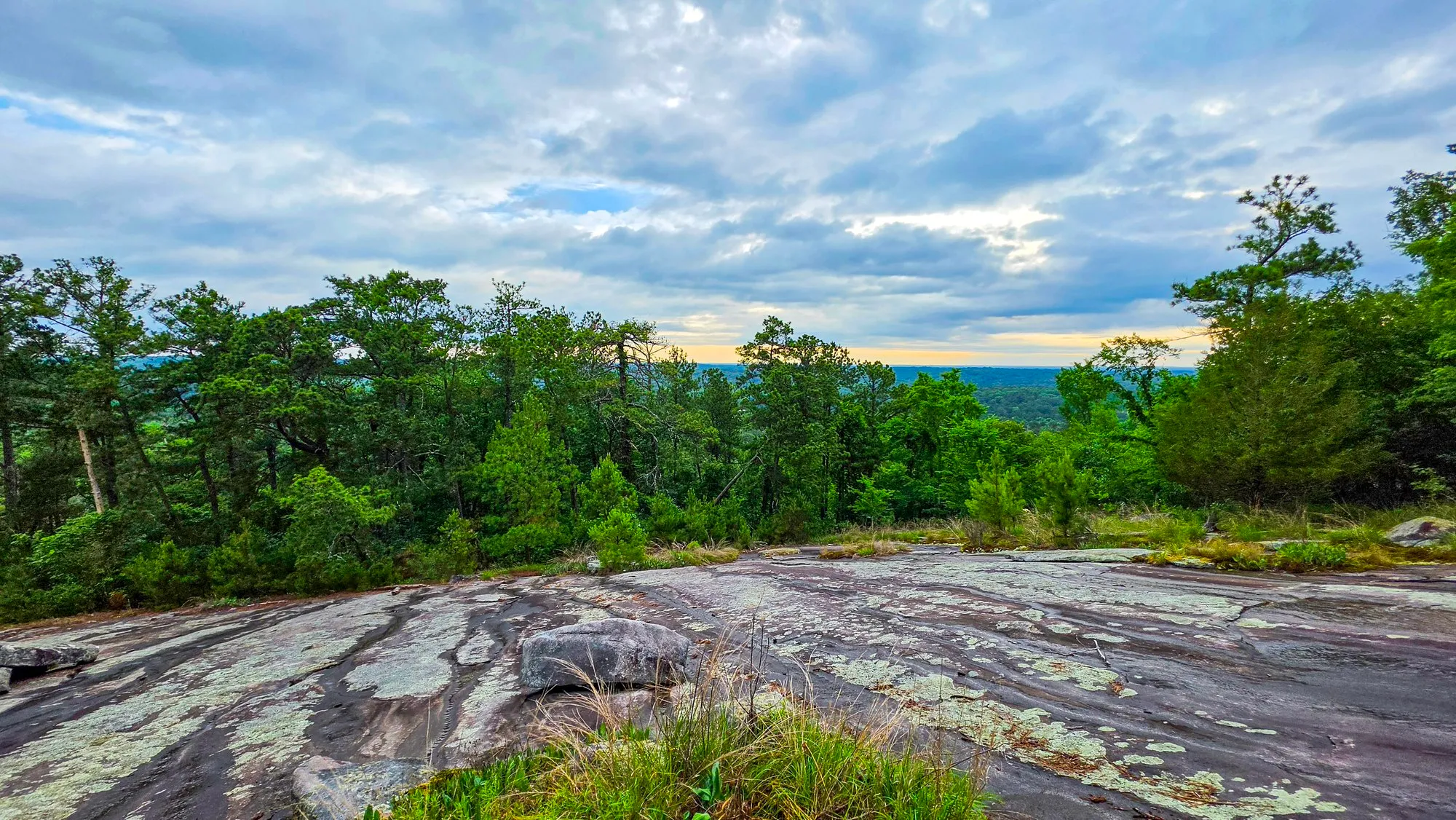 Broken cloud over the bare granite top of Stone Mountain, pines and green woods at its edge, hazy country beyond