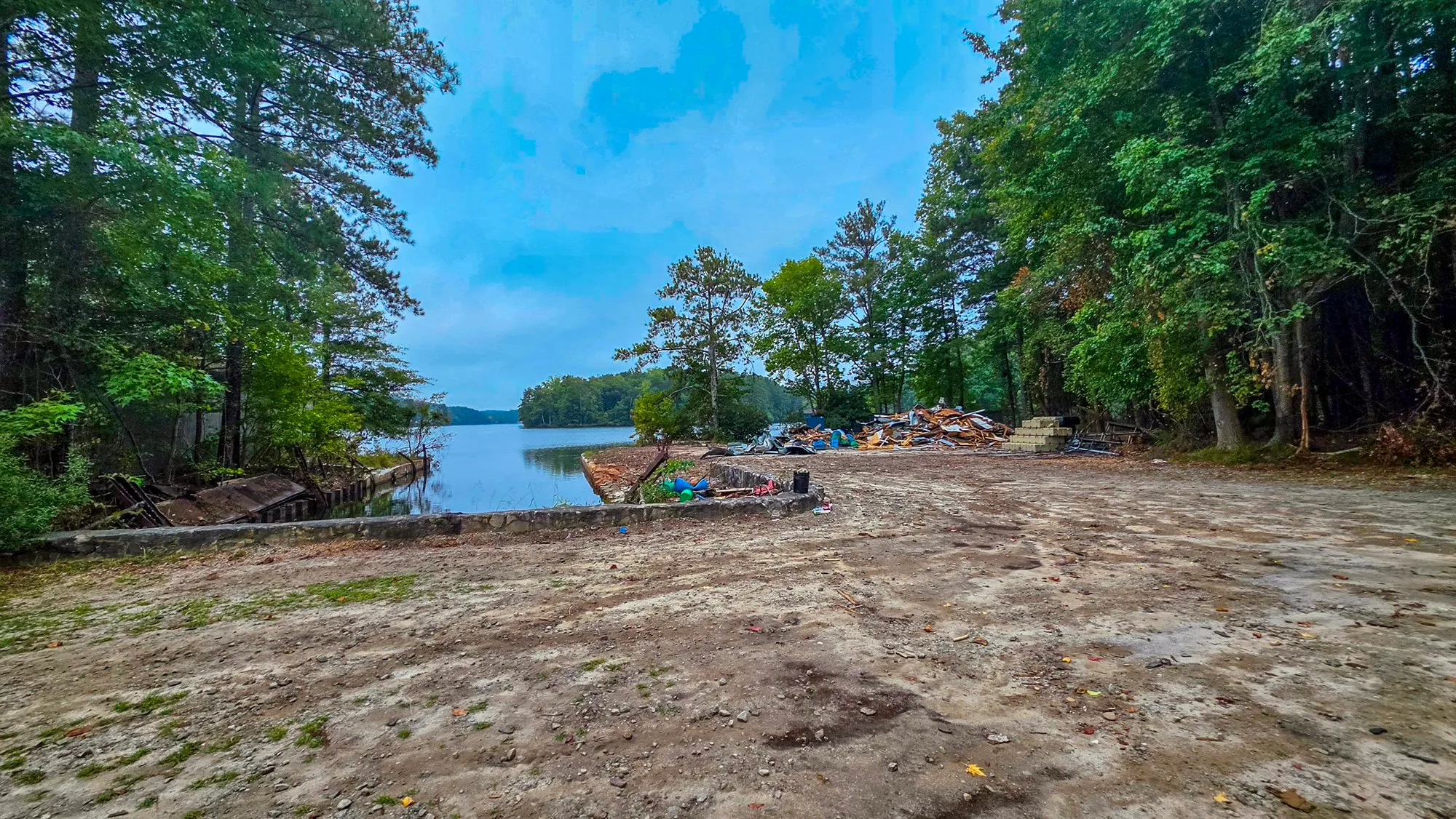 The cleared corner of the dry dock: bare ground out to the seawall, a heap of rubble and cut timber where the paddlewheel boat and the old storage building stood, the lake beyond